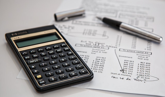 Desk with a calculator, sheet of paper, and pen